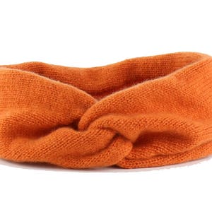 May include: A bright orange knitted headband with a twisted knot design.