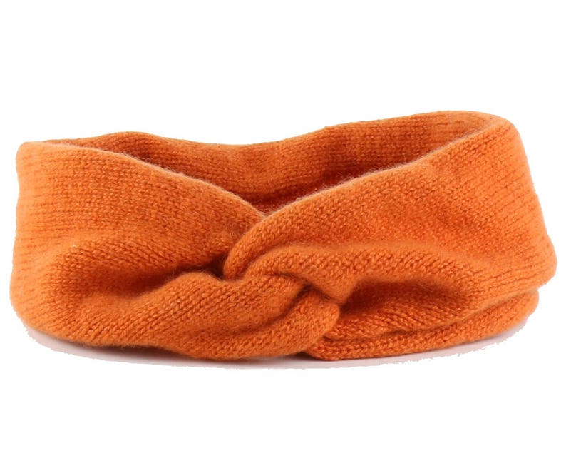 May include: A bright orange knitted headband with a twisted knot design.
