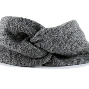 May include: A gray knitted headband with a twisted knot design.