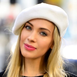 The model is wearing a white wool beret.