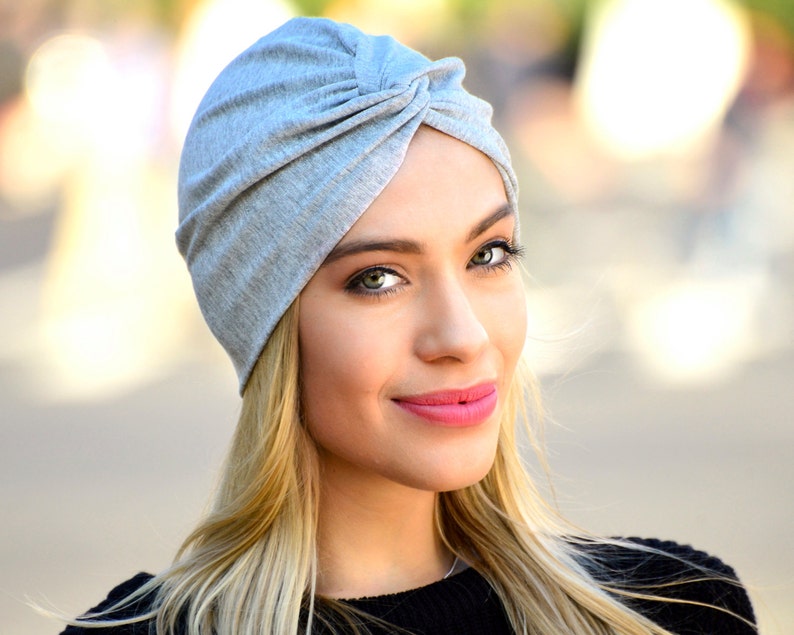The model is wearing a turban style hat sewn from silver jersey fabric.