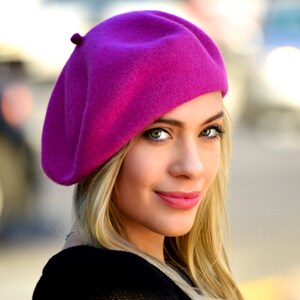 The model is wearing a magenta beret.