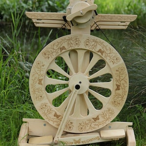 May include: A wooden spinning wheel with a large, intricately carved wheel and a smaller, decorative wheel on top. The wheel is decorated with a floral design and butterflies.