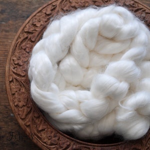 May include: White cotton fiber filling in a carved wooden bowl. The bowl has a floral design.