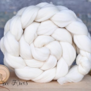 May include: A white, braided ball of wool fiber. The fiber is arranged in a spiral pattern and is ready for spinning.