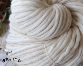 May include: A close-up of a skein of thick, white yarn. The yarn is soft and fluffy, and it is perfect for knitting or crocheting.