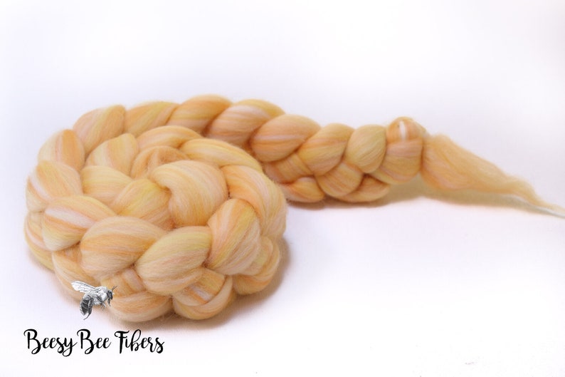 Puede incluir: Una trenza de hilo de lana de color naranja claro y blanco. El hilo est&aacute; trenzado de forma suelta y relajada. El hilo es suave y esponjoso, y ser&iacute;a perfecto para tejer o hacer ganchillo.