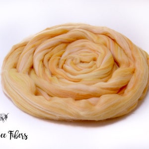 Puede incluir: Primer plano de una fibra suave y esponjosa de color melocot&oacute;n. La fibra est&aacute; dispuesta en espiral, creando una forma circular.