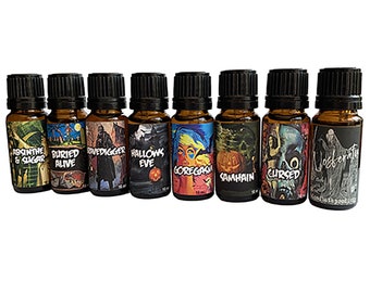 May include: Ten small brown glass bottles with black caps and colorful labels. The labels feature Halloween-themed illustrations and text, such as "Absinthe & Sugar", "Buried Alive", "Grave Digger", "Hallows Eve", "Goregasm", "Samhain", "Cursed", and "Nosferatu".