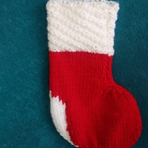Peut inclure: Une chaussette de Noël rouge et blanche en tricot avec un revers blanc.