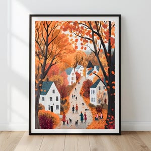 Puede incluir: Una lámina artística enmarcada que representa un camino sinuoso a través de un pueblo en otoño. La escena muestra casas blancas, árboles altos con follaje naranja y rojo, y pequeñas figuras caminando con perros por la carretera bajo los árboles.