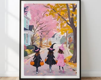 May include: A framed art print depicts three young figures in witch costumes walking down a street, each carrying a pumpkin bucket. The artwork features a pink and yellow autumn color palette, with houses and trees lining the street.