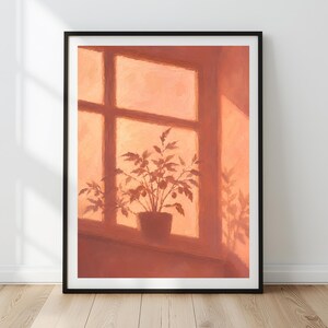 Könnte beinhalten: Ein gerahmter Kunstdruck mit einem gemalten Motiv einer Topfpflanze auf einem Fensterbrett. Das Kunstwerk verwendet eine warme, monochrome Farbpalette in Terrakotta- und Pfirsichtönen und zeigt Licht, das durch eine Fensterscheibe auf die Pflanze fällt.