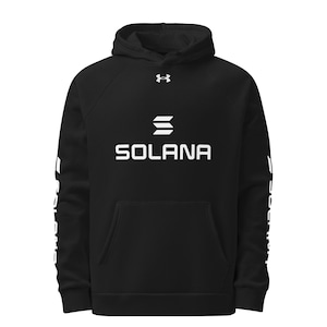 Può includere: Felpa con cappuccio nera con la scritta "SOLANA" a lettere bianche sul petto. Il logo Under Armour è visibile sopra la parola. Testo bianco stampato sulle maniche. La felpa ha una tasca frontale.