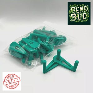 May include: A bag of teal green plastic hooks with a single hook displayed outside the bag. The hook has a rotating mechanism and two prongs. The bag has a sticker that says "Made in U.S.A.".