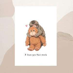 May include: A greeting card featuring an illustration of a gray monkey hugging a brown stuffed animal. A small pink heart floats above them. The text "I love you this much" is printed below the illustration.