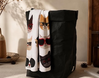 May include: A black storage bin with a white fabric panel featuring a repeating pattern of cat faces wearing various styles of glasses and sunglasses. The bin has a structured, rectangular shape with a folded top edge and a matte finish.
