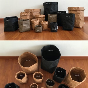 Puede incluir: Un conjunto de 11 bolsas de papel marr&oacute;n con forros de tela negra, numeradas del 1 al 11. Las bolsas est&aacute;n dispuestas en dos filas, con las bolsas m&aacute;s grandes en la parte posterior y las m&aacute;s peque&ntilde;as en la parte delantera. Las bolsas est&aacute;n todas vac&iacute;as.