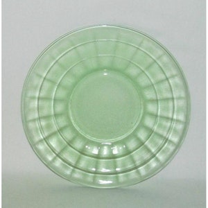 May include: A light green glass saucer with a rippled design. The saucer has a smooth, shiny surface.