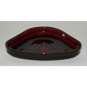 May include: A dark red glass corner dish with a scalloped edge.