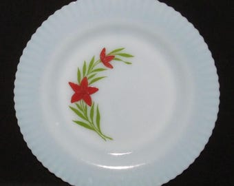 May include: A white plate with a scalloped edge and a floral design. The plate features a red flower and green leaves. The plate is a vintage style and is suitable for serving food.