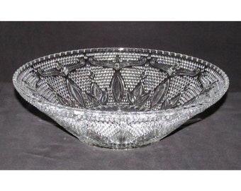 May include: A clear glass serving bowl with a decorative, raised pattern of leaves and dots. The bowl has a scalloped edge.