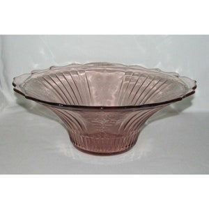 May include: A large, clear, pink glass bowl with a scalloped edge and a fluted design. The bowl is perfect for serving fruit, salads, or other dishes.