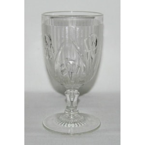 May include: A clear glass goblet with a stemmed base and a decorative pattern of flowers and leaves.
