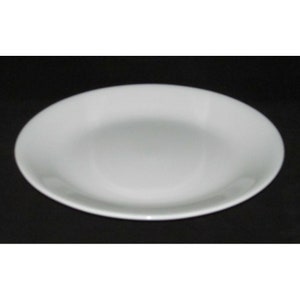 May include: A white ceramic dinner plate with a slightly raised rim.
