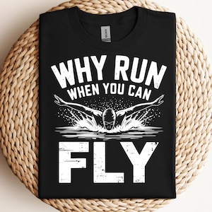 May include: Black t-shirt with white text that reads "Why run when you can fly". The shirt features a silhouette of a swimmer in mid-air.