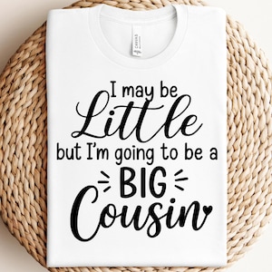 以下が含まれることがあります： 白いTシャツに黒い文字で「小さいかもしれないけど、大きないとこになるんだ」と書かれています。