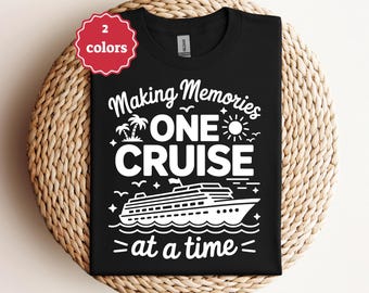 May include: Black t-shirt with white text that reads "Making Memories ONE CRUISE at a time." The design includes a cruise ship, sun, palm trees, and birds. A red tag in the upper left corner says "2 colors."