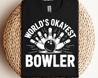 May include: Black t-shirt with a white graphic featuring a bowling ball and pins. The text reads "WORLD'S OKAYEST BOWLER" in a bold, sans-serif font. The shirt is made of a soft material and is suitable for casual wear.
