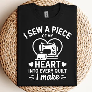 以下が含まれることがあります： 白いグラフィックが特徴の黒いTシャツ。テキストは「I sew a piece of my heart into every quilt I make」と書かれています。デザインには、ハートの形をしたミシン、ハートと矢印の追加の詳細が含まれています。