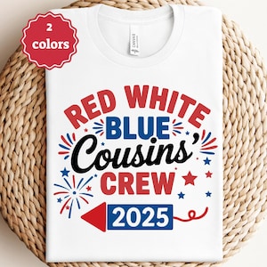 May include: White t-shirt with a patriotic design featuring the words "RED WHITE BLUE Cousins' CREW 2025" in red, white, and blue. The design includes stars, fireworks, and a red arrow. A red circle with the text "2 colors" is in the upper left corner.
