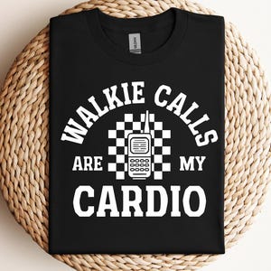 May include: Black t-shirt with white text that reads "Walkie Calls Are My Cardio". The text is surrounded by a checkered pattern and a graphic of a walkie talkie.