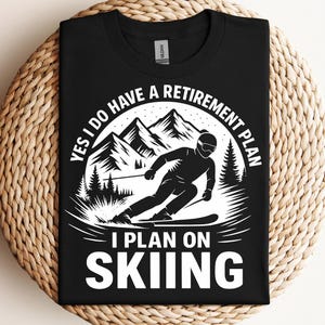 May include: Black t-shirt with white text that reads "Yes I do have a retirement plan I plan on skiing" with a graphic of a skier in a mountain landscape.