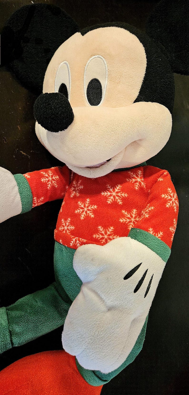 Puede incluir: Un juguete de peluche de Mickey Mouse con un su&eacute;ter navide&ntilde;o rojo y verde con copos de nieve blancos. El juguete tiene una nariz negra y grandes ojos negros.
