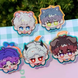 May include: Six colorful cartoon character pins with a holographic finish. Each pin features a different character with a unique hairstyle and expression. The characters are wearing different outfits and accessories.