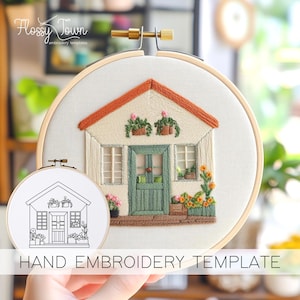 Könnte beinhalten: Eine Hand-Stickvorlage mit einem kleinen Haus mit einer grünen Tür, einem orangenen Dach und weißen Verzierungen. Das Haus hat Fenster, eine Veranda und Blumen in Töpfen. Die Vorlage ist auf weißem Hintergrund und von einem hölzernen Stickrahmen umgeben.