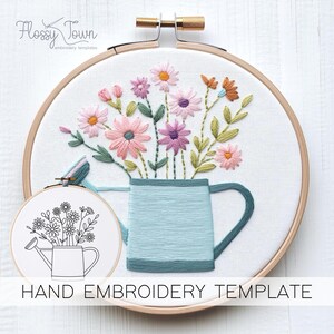 Könnte beinhalten: Eine Hand-Stickvorlage mit einer Gießkanne, die mit einem Strauß rosa, lila und orangefarbener Blumen gefüllt ist. Die Vorlage ist auf weißem Stoff gedruckt und bereit zum Sticken.