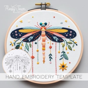May include: A hand embroidery template featuring a colorful dragonfly with floral accents and stars. The template is in a hoop and includes a black and white line drawing of the design.