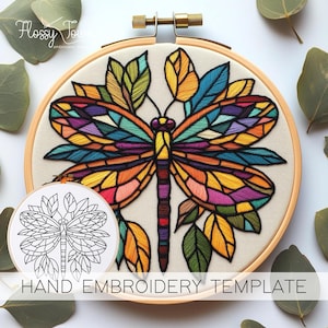 May include: A hand embroidery template featuring a colourful dragonfly with stained glass-like wings surrounded by leaves. The template is printed on white paper and is ready to be used for embroidery.