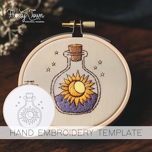 May include: A hand embroidery template featuring a glass bottle with a cork stopper. The bottle contains a sun and moon design with purple and yellow embroidery floss. The template is on a white background with the text "HAND EMBROIDERY TEMPLATE".