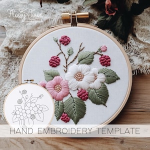 Puede incluir: Una plantilla de bordado a mano con un diseño floral con flores rosas y blancas, hojas verdes y bayas rojas. La plantilla está en un aro redondo y está etiquetada como "HAND EMBROIDERY TEMPLATE".