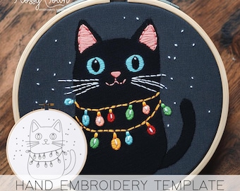 Puede incluir: Patrón de bordado de gato negro con una cadena de luces de colores alrededor del cuello. El patrón está en un aro e incluye una versión más pequeña del diseño.