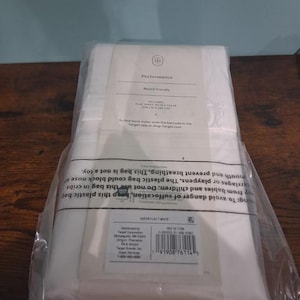 May include: A package of white flat sheets labeled "Performance" and "Bleach friendly." The package includes a flat sheet measuring 94 x 104 inches. The packaging also includes a barcode and care instructions.