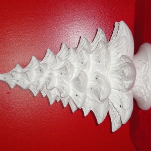 May include: White ceramic Christmas tree ornament with a textured surface. The tree is made up of multiple layers and has a base.
