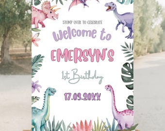 Puede incluir: Un letrero de bienvenida para una fiesta de primer cumpleaños, con ilustraciones de acuarela de dinosaurios y follaje tropical. El letrero dice "Welcome to Emersyn's 1st Birthday" con la fecha 17.03.20XX. El letrero está en un caballete de madera.