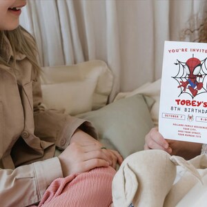 May include: A red and blue Spiderman cartoon character is on a birthday invitation for an 8th birthday party. The invitation says "You're invited to Tobey's 8th Birthday" and includes the date, time, and location of the party.